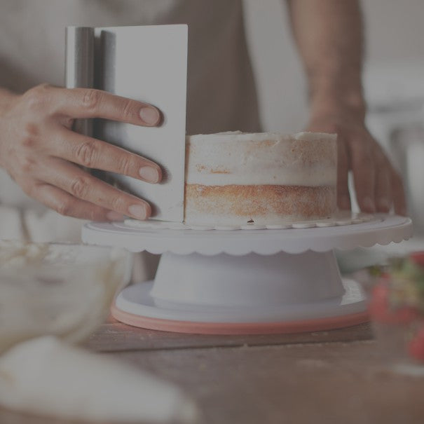 Person using a cake leveler to levela layered cake on a white stand.