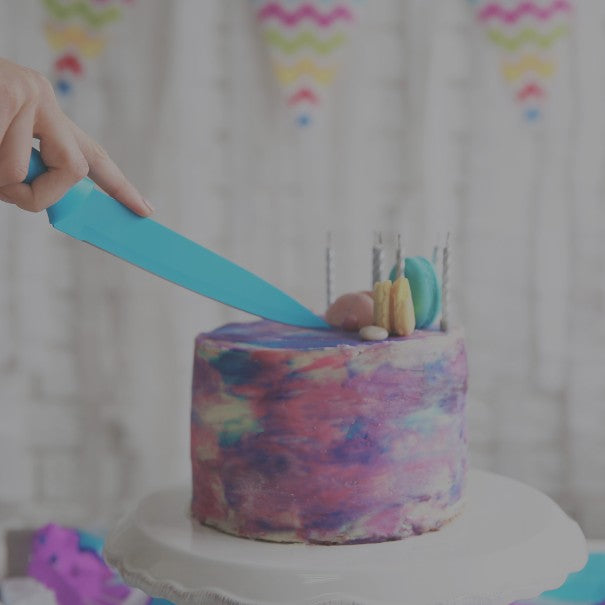 Colorful cake with a hand holding a blue knife