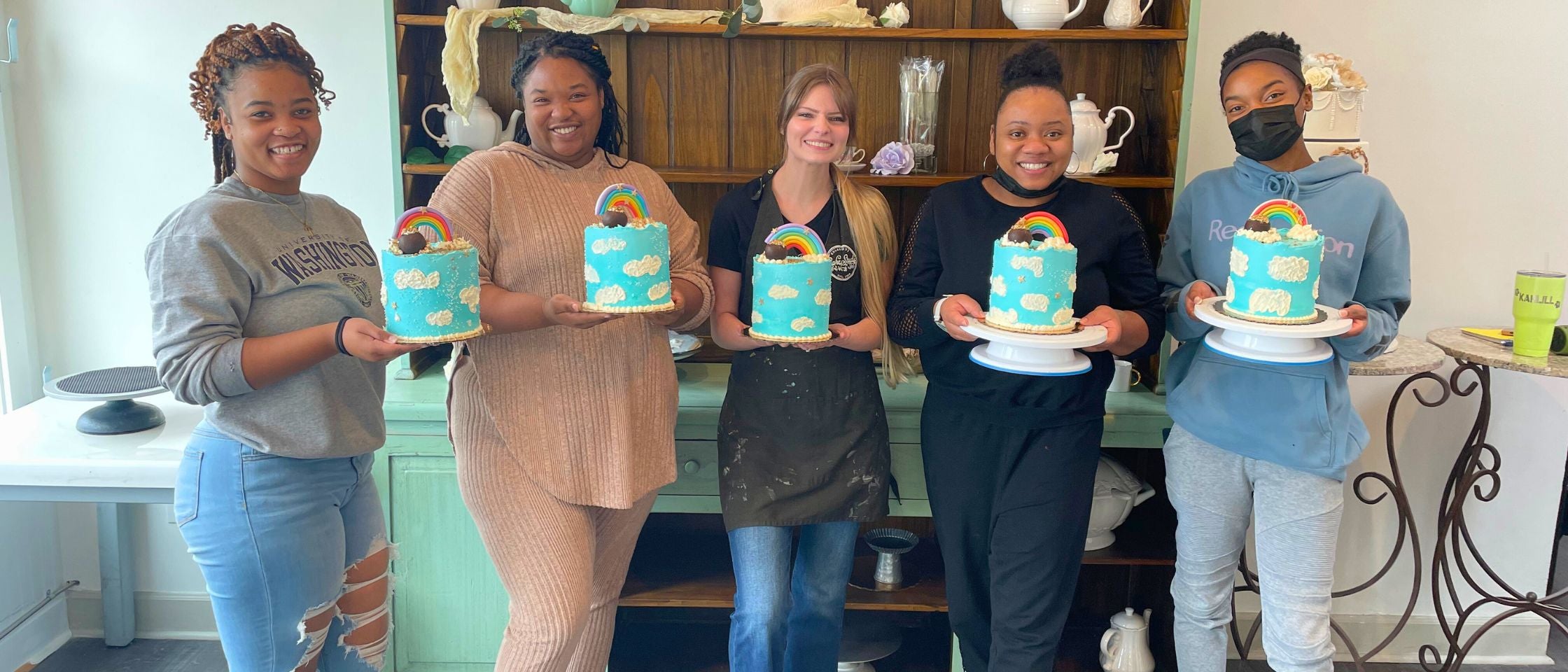 five women holding a blue cake