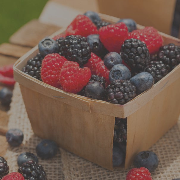 Wooden basket filled with mixed berries on a rustic surface