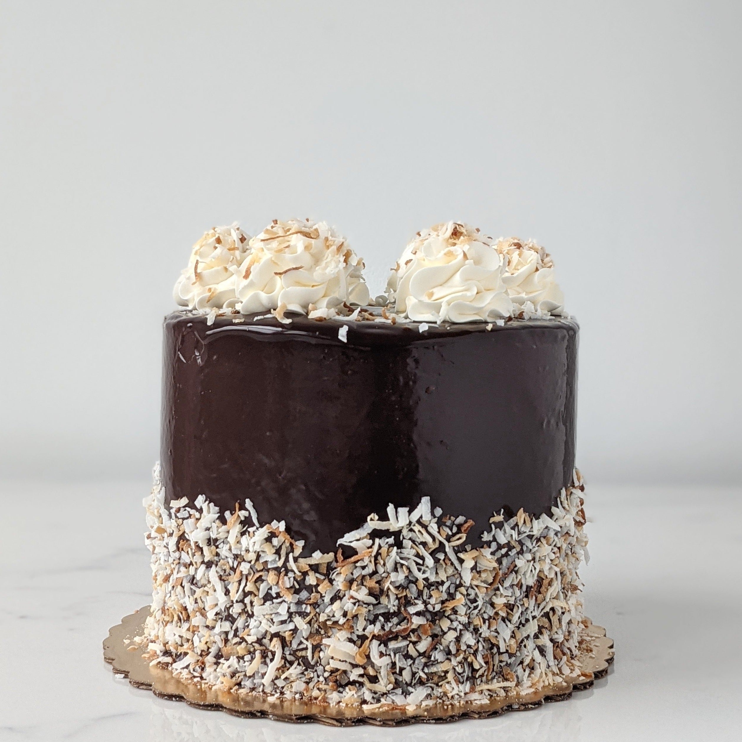 A chocolate coconut cake with vanilla buttercream icing and decorated with toasted coconut flakes and chocolate ganache.