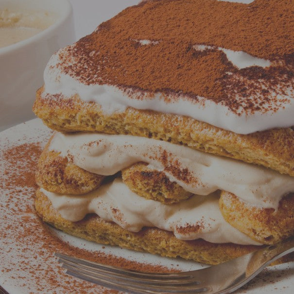 Layered dessert with whipped cream and cinnamon powder on a plate