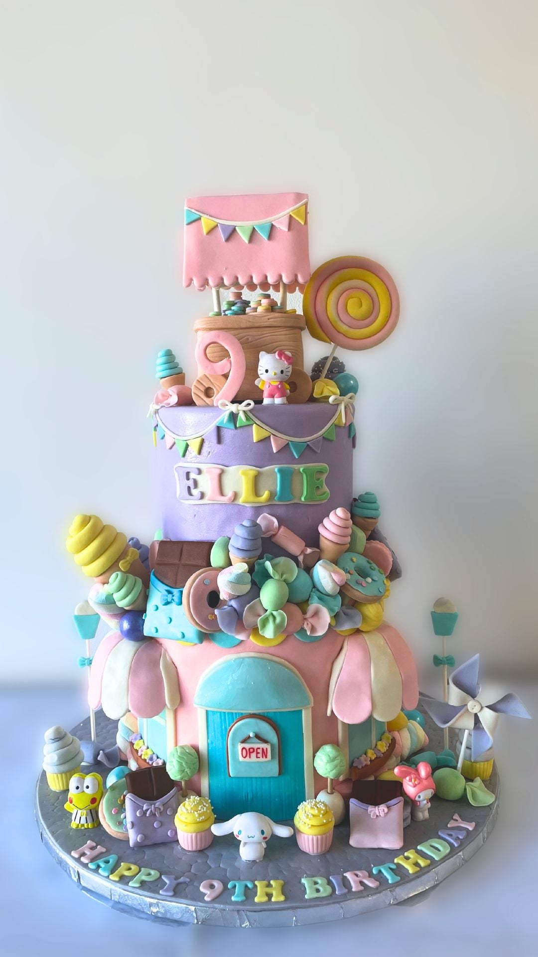 A multi-tiered cake decorated with sweets and featuring a Sanrio character theme.