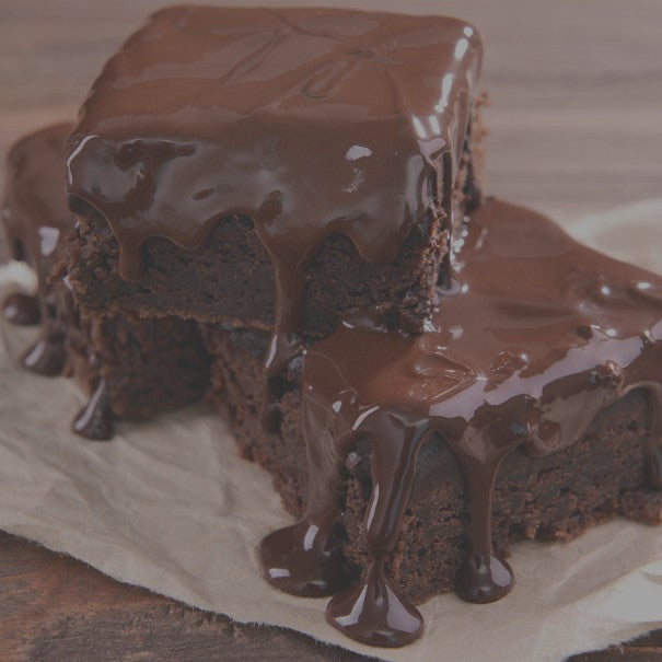 Chocolate brownies with glossy chocolate glaze on a wooden surface