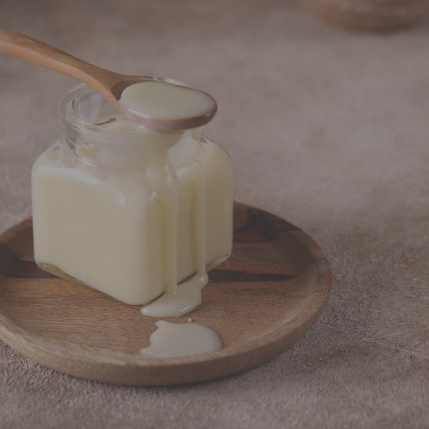 Jar of cream with a wooden spoon on a wooden plate