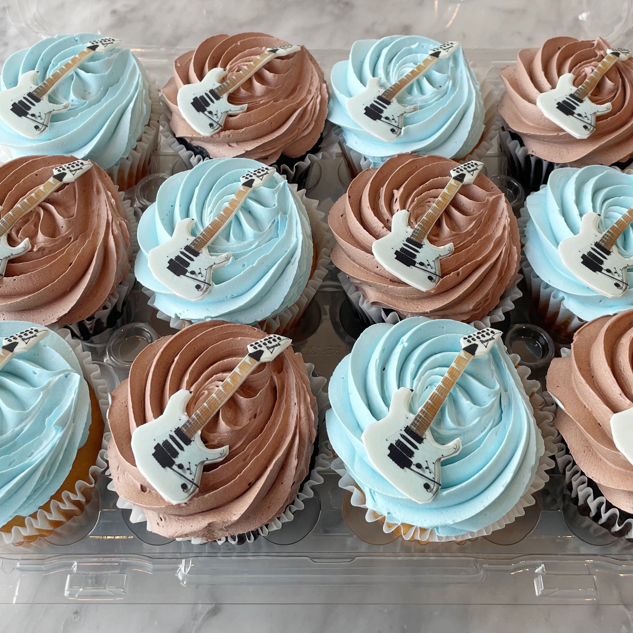 Cupcakes decorated with blue and brown swirled frosting, with guitar