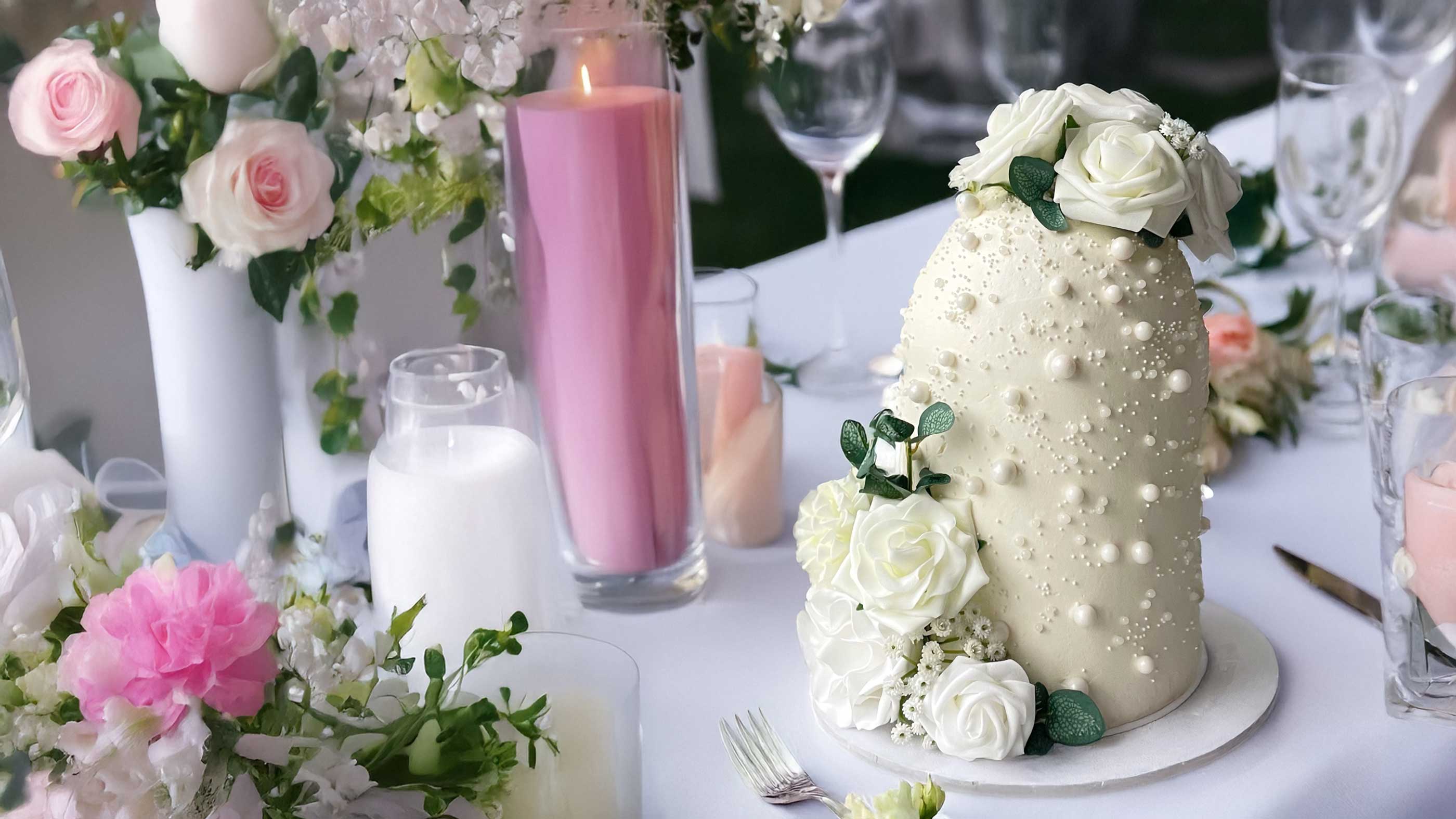 White floral wedding cake with small white flowers on a decorated table