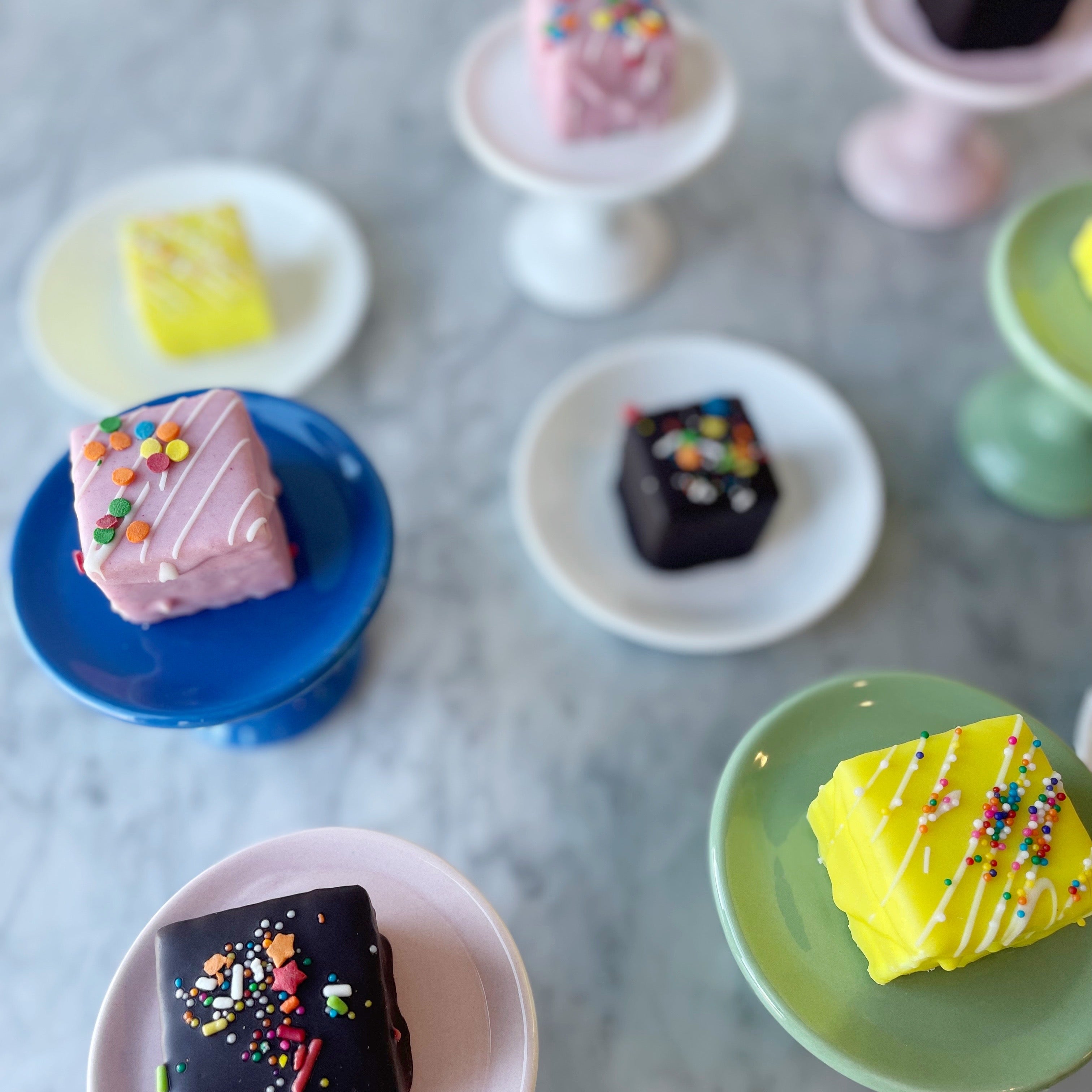 Colorful small cakes on various colored plates