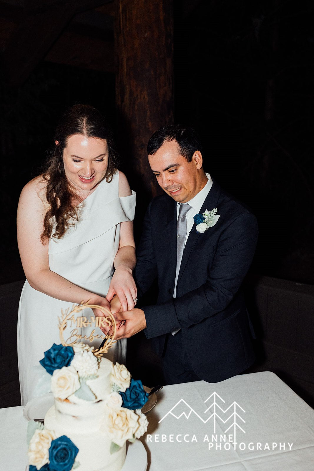A bride and groom cutting a wedding cake. Designed with blue and white flowers.