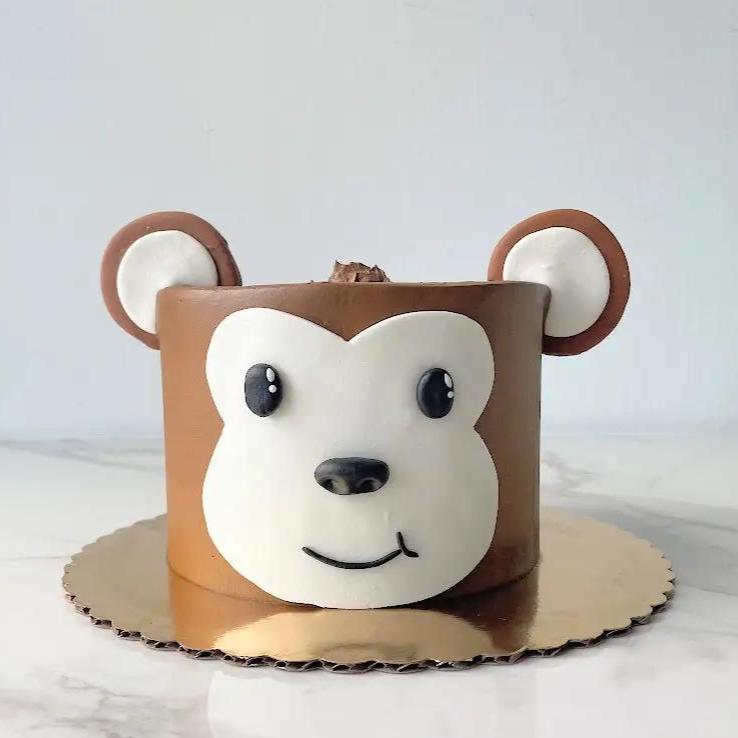 A cake decorated to look like a monkey's face. The cake is brown with a tan face and two brown, rounded ears.