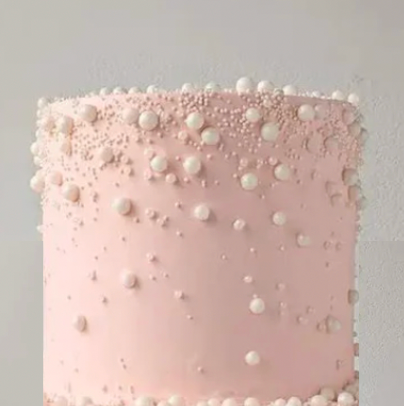 A light pink cake decorated with small white pearls or dragees