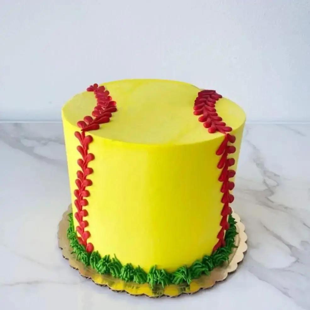 A round, yellow cake with two red seams on the side, decorated to look like a softball.