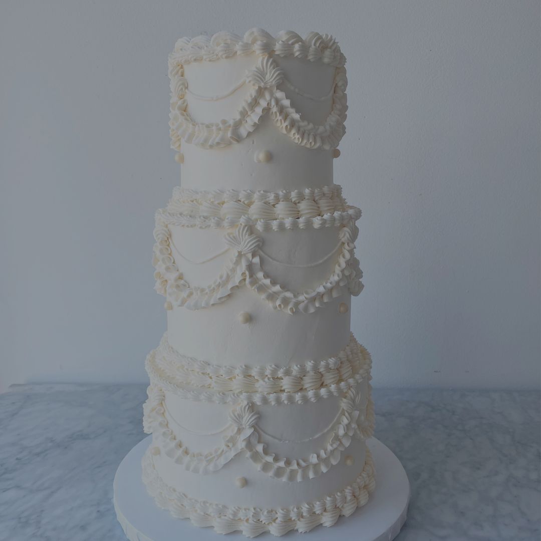 White wedding cake with decorative patterns on a marble surface