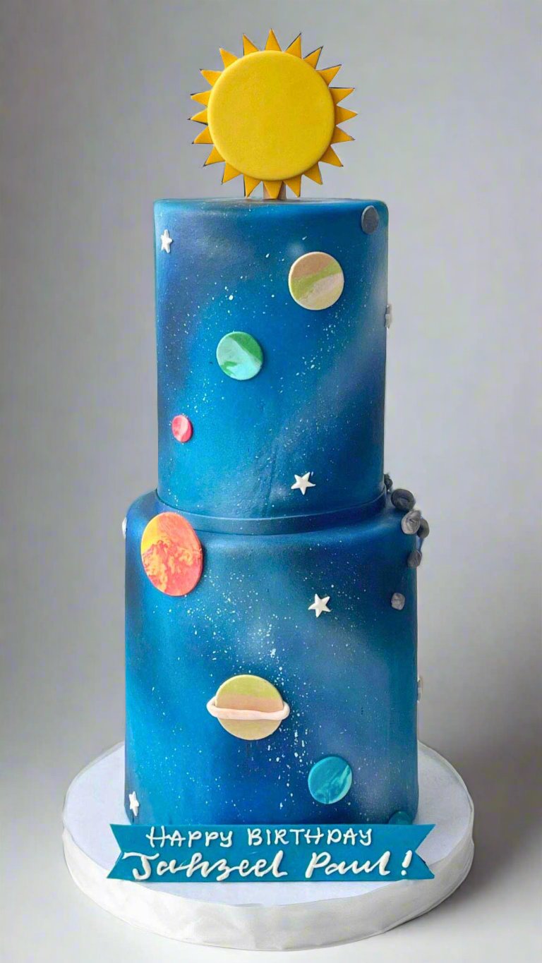 Two-tiered galaxy-themed cake decorated with planets, stars, and a sun topper