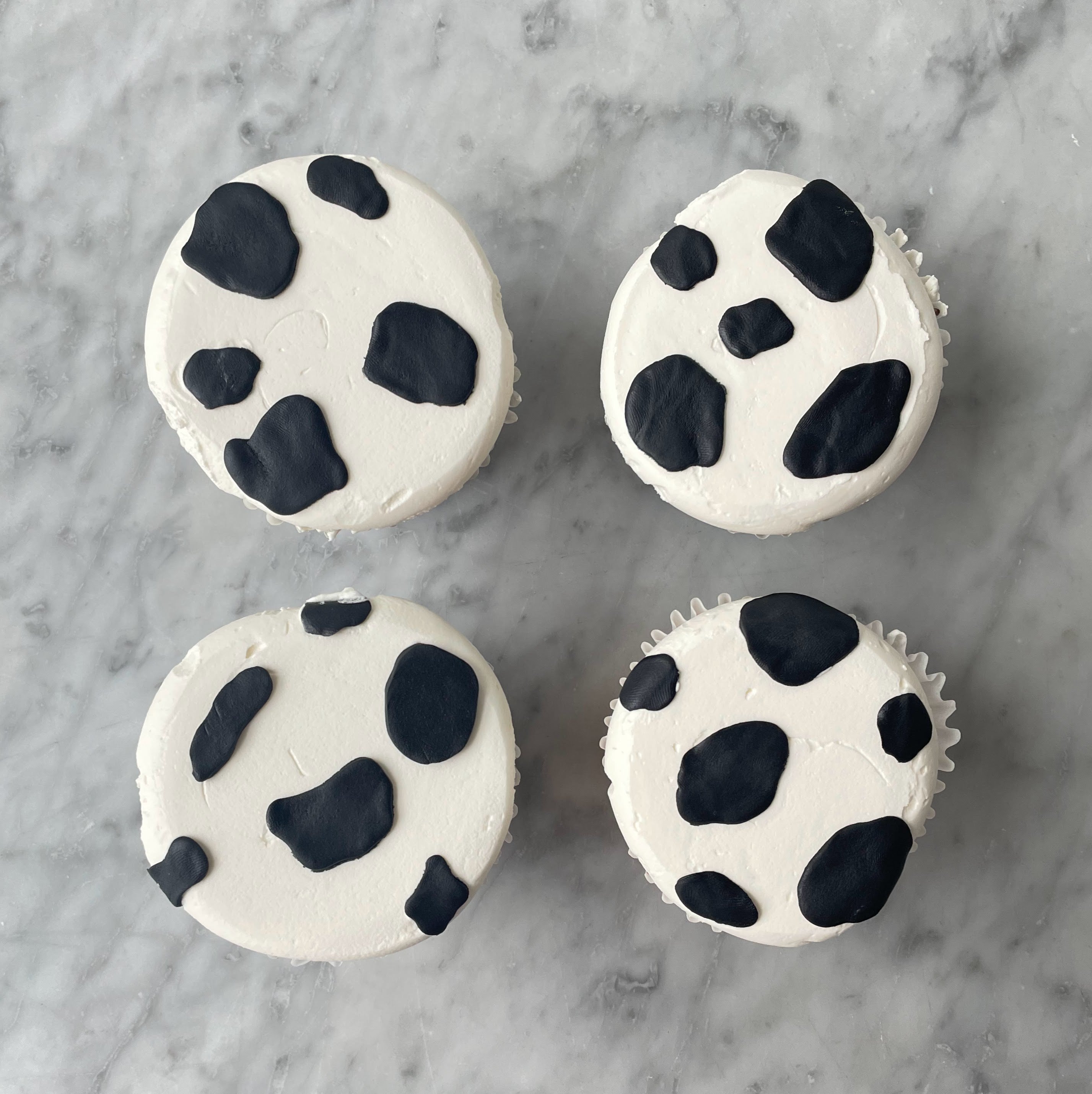 Close-up of four cupcakes decorated with black and white cow spots