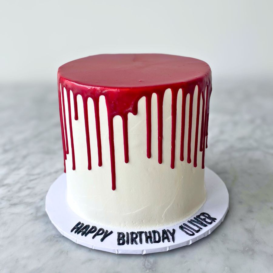 Cake with red drip design on a white marble surface