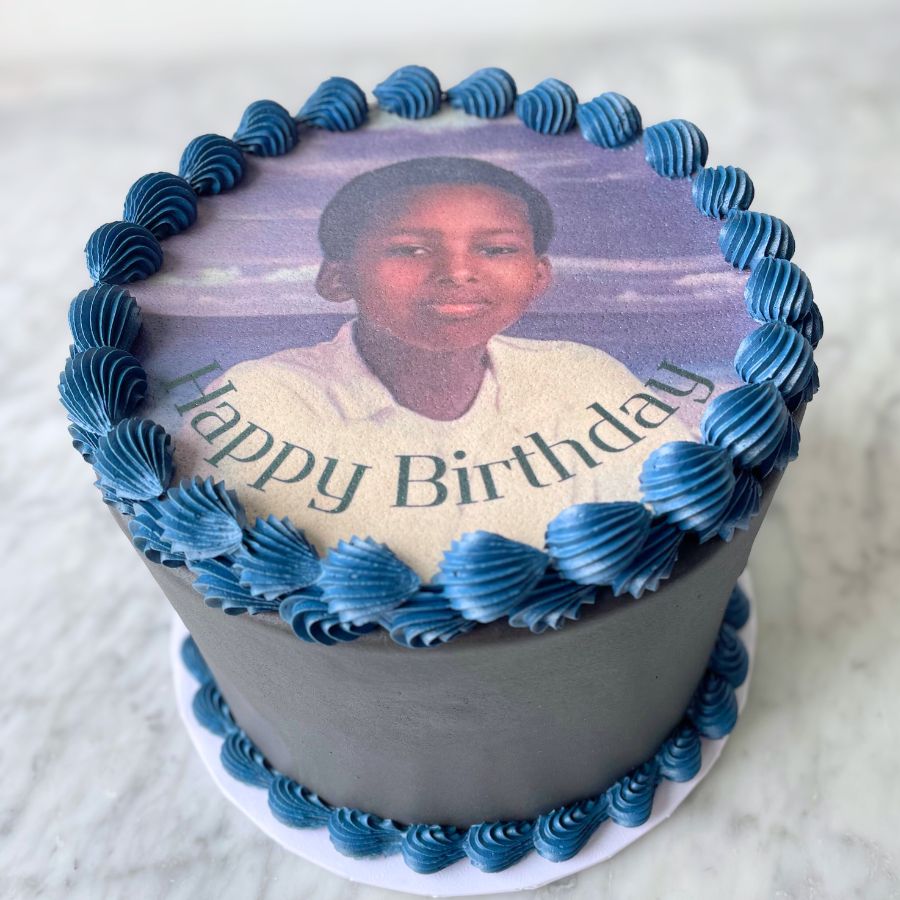 Birthday cake with blue icing and a photo of a young boy at the top