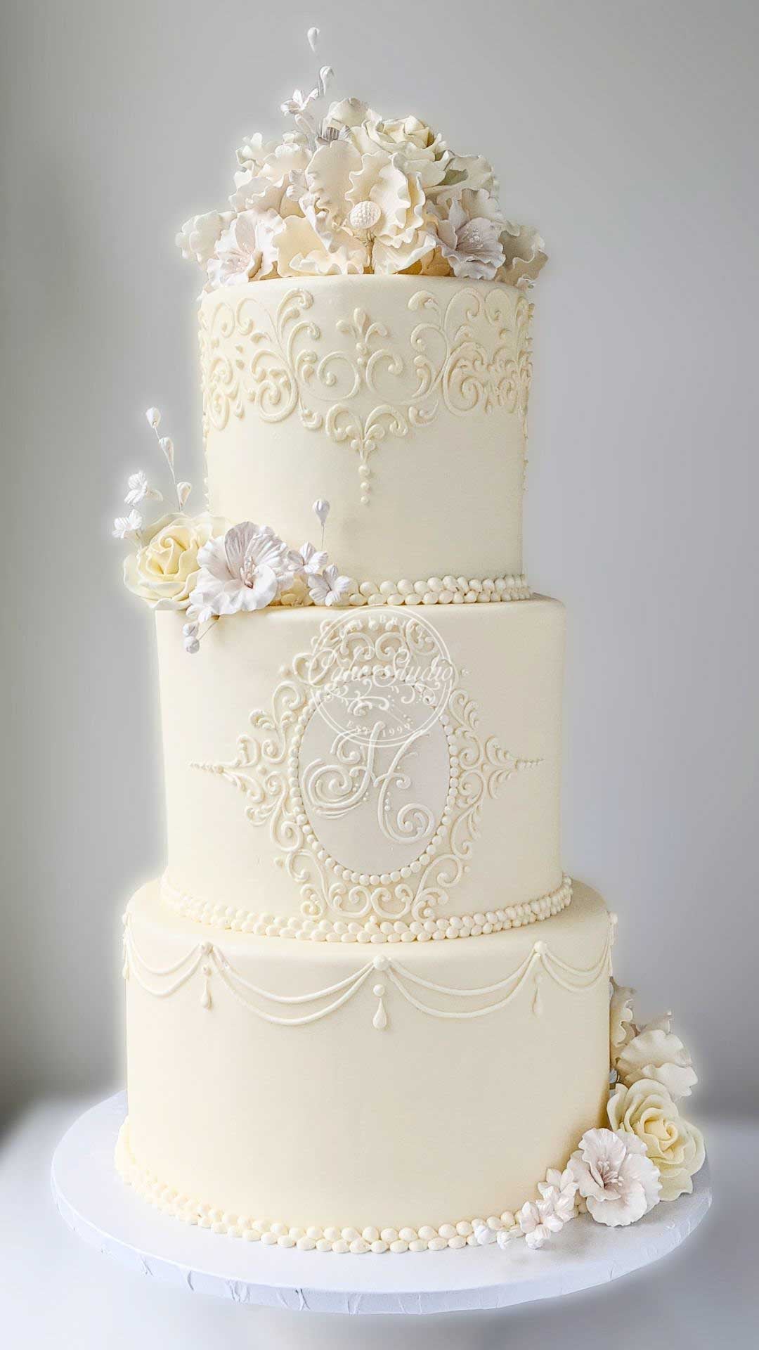 A three-tiered white wedding cake with a textured pattern, decorated with white and yellow flowers.
