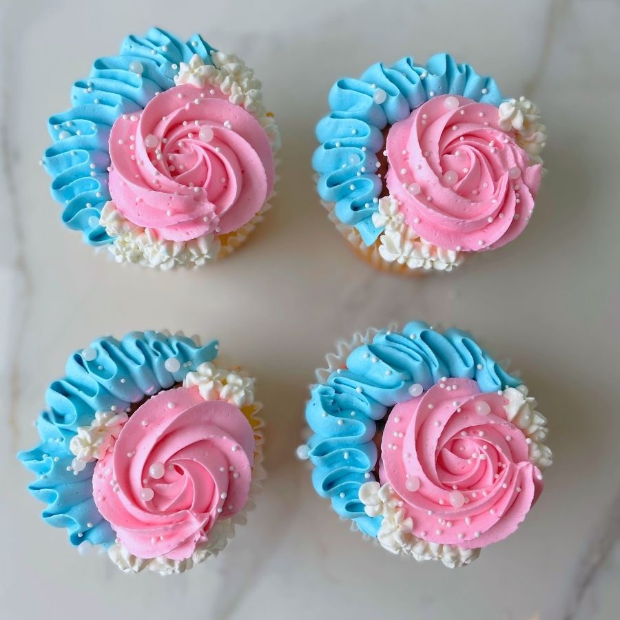 gender reveal cupcakes with pink and blue frosting on a white background