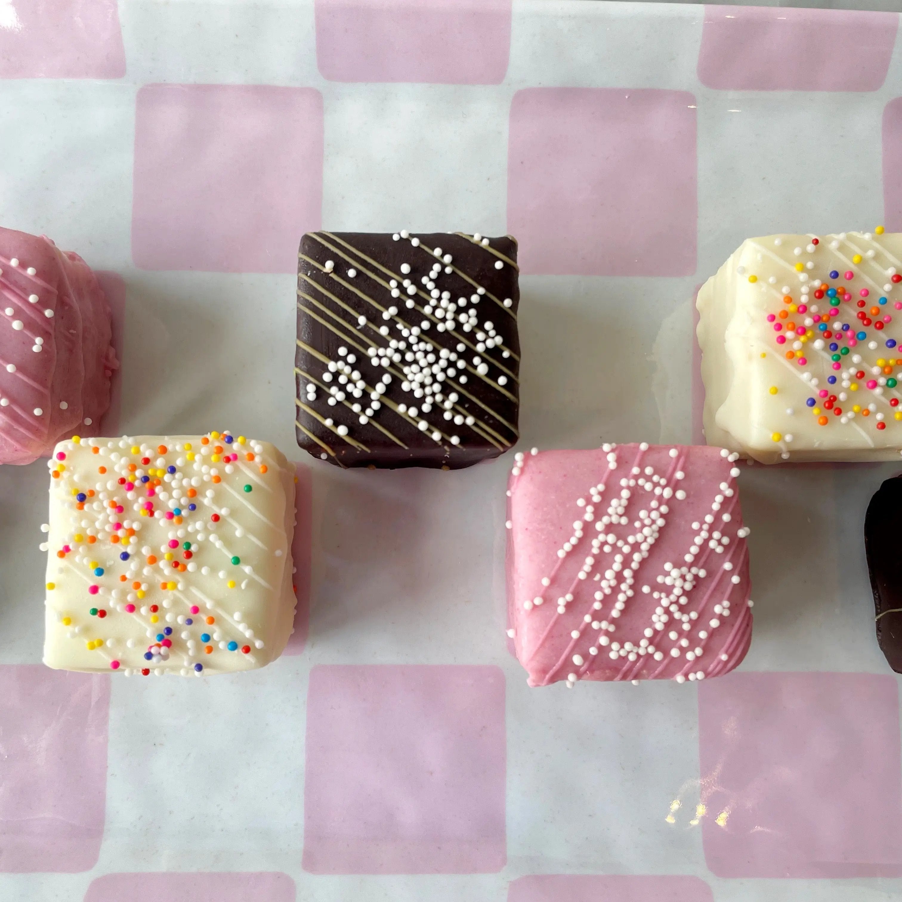 Decorative petit fours with sprinkles on a pink checkered plate