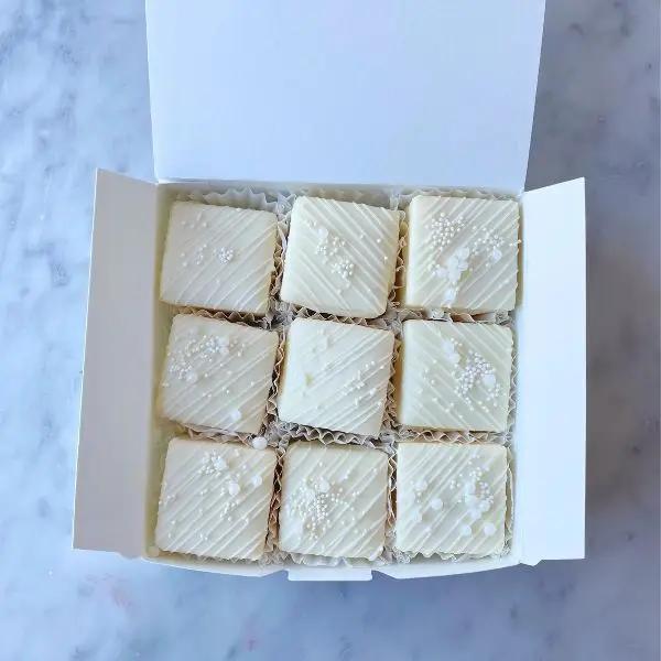 white square tea cakes with white chocolate drizzle and edible pearls