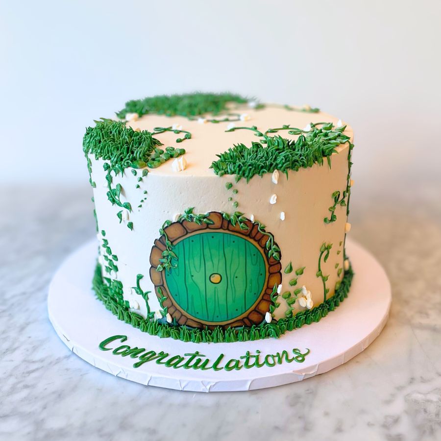 Hobbit-themed celelbration cake with grass and a green door, on a white background.