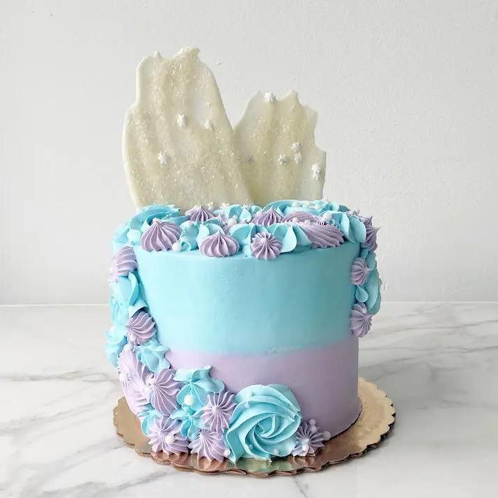A two-toned cake with light blue and purple frosting with blue and purple frosting cascading from top to side, then botttom.