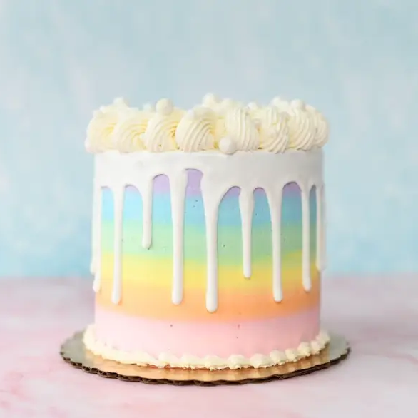 A colorful Pastel Rainbow Cake with layers and a smooth vanilla buttercream frosting, with pastel rainbow colors visible on the sides.