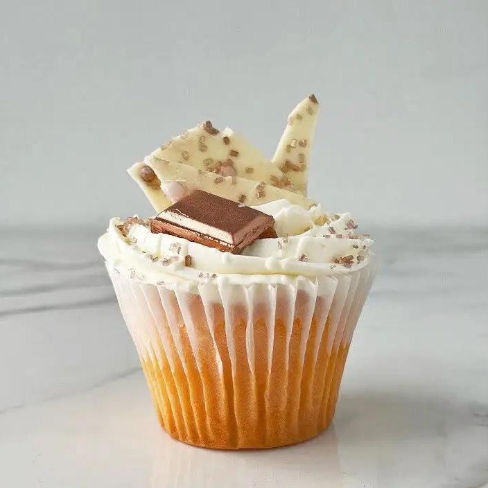 A vanilla cupcake with white frosting, light brown chocolate and candy decorations.