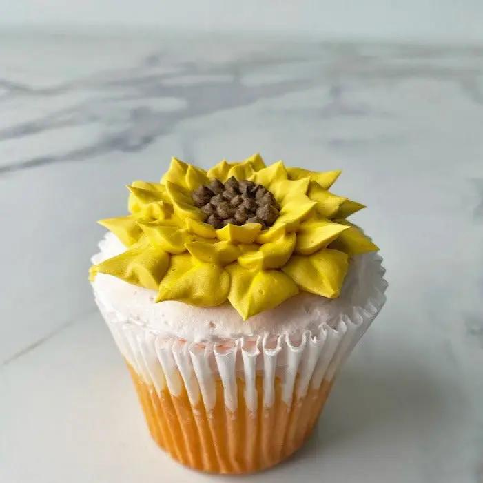 A cupcake with yellow frosting shaped to look like a sunflower.
