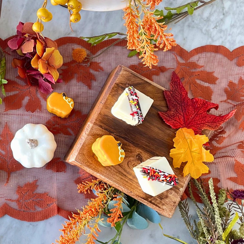 Autumn-themed treats square cakes with a chocolate drizzle and sprinkles, and a few small pumpkin-shaped cake.