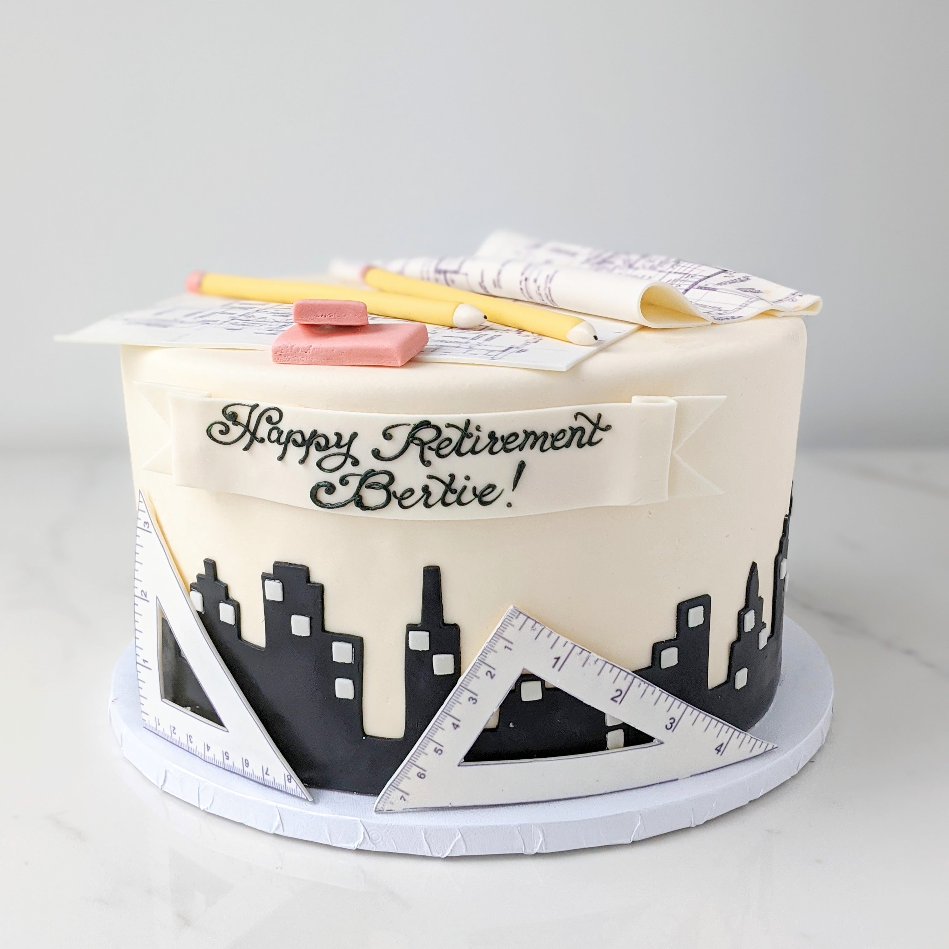 Cake with retirement-themed decorations including a ruler, eraser, and pencil 