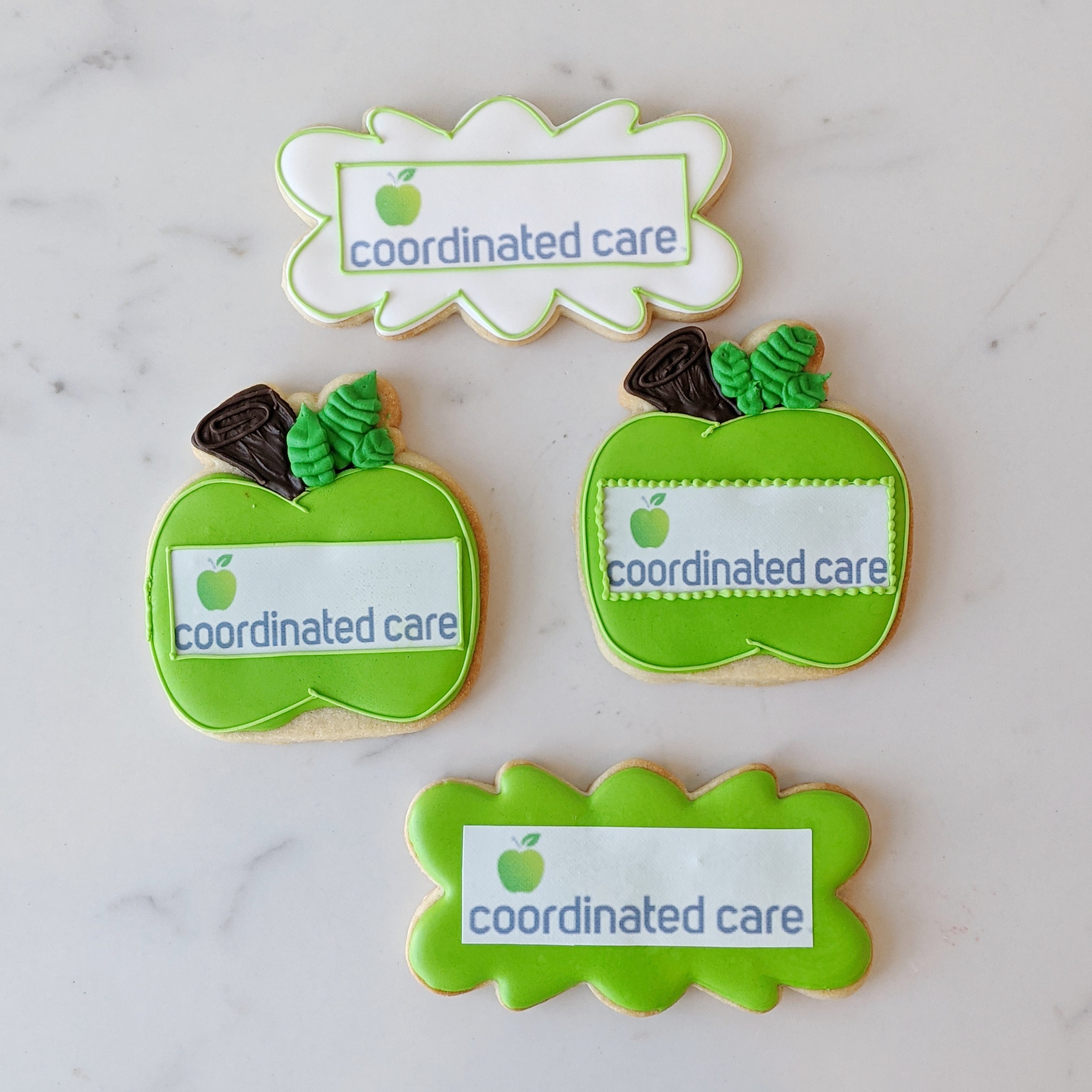 Green apple-shaped cookies with 'coordinated care' branding on a marble surface
