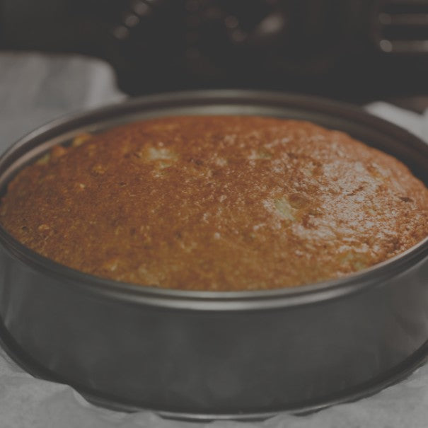 Baked cake in a round metal pan on a gray surface