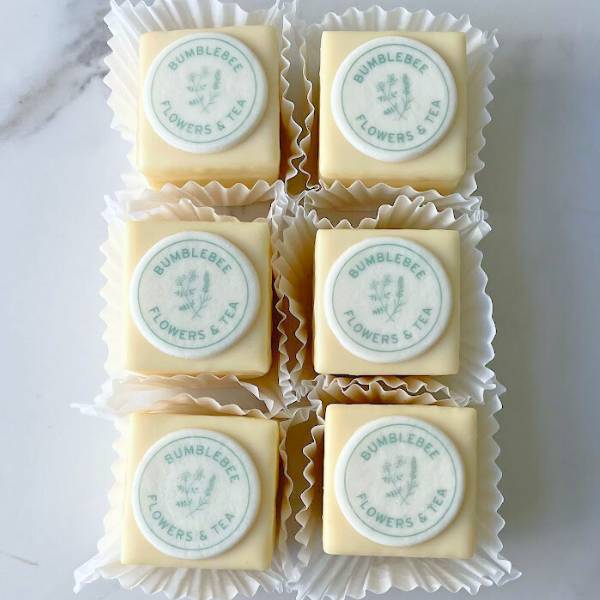 Six square candies with 'Bumblebee Flowers & Tea' label on a white marble surface