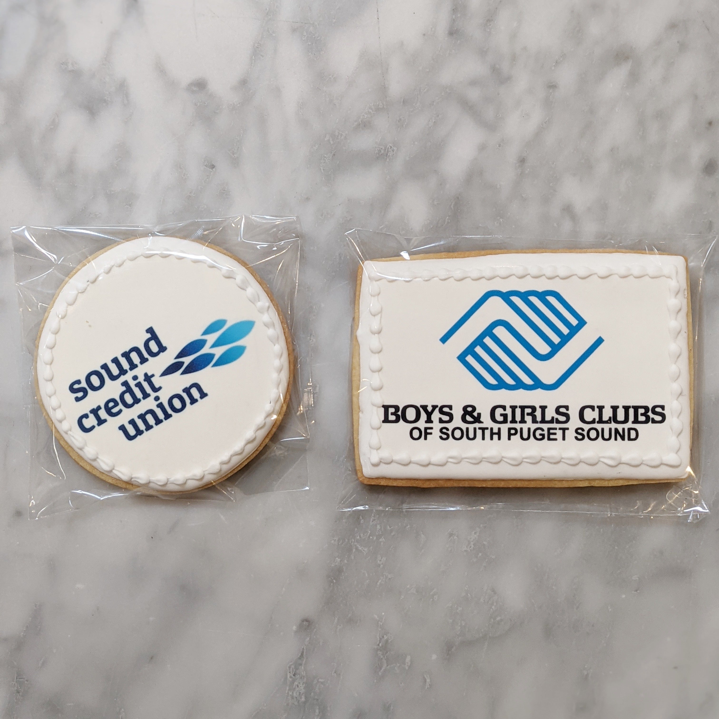 Two cookies with branded logos on a marble surface
