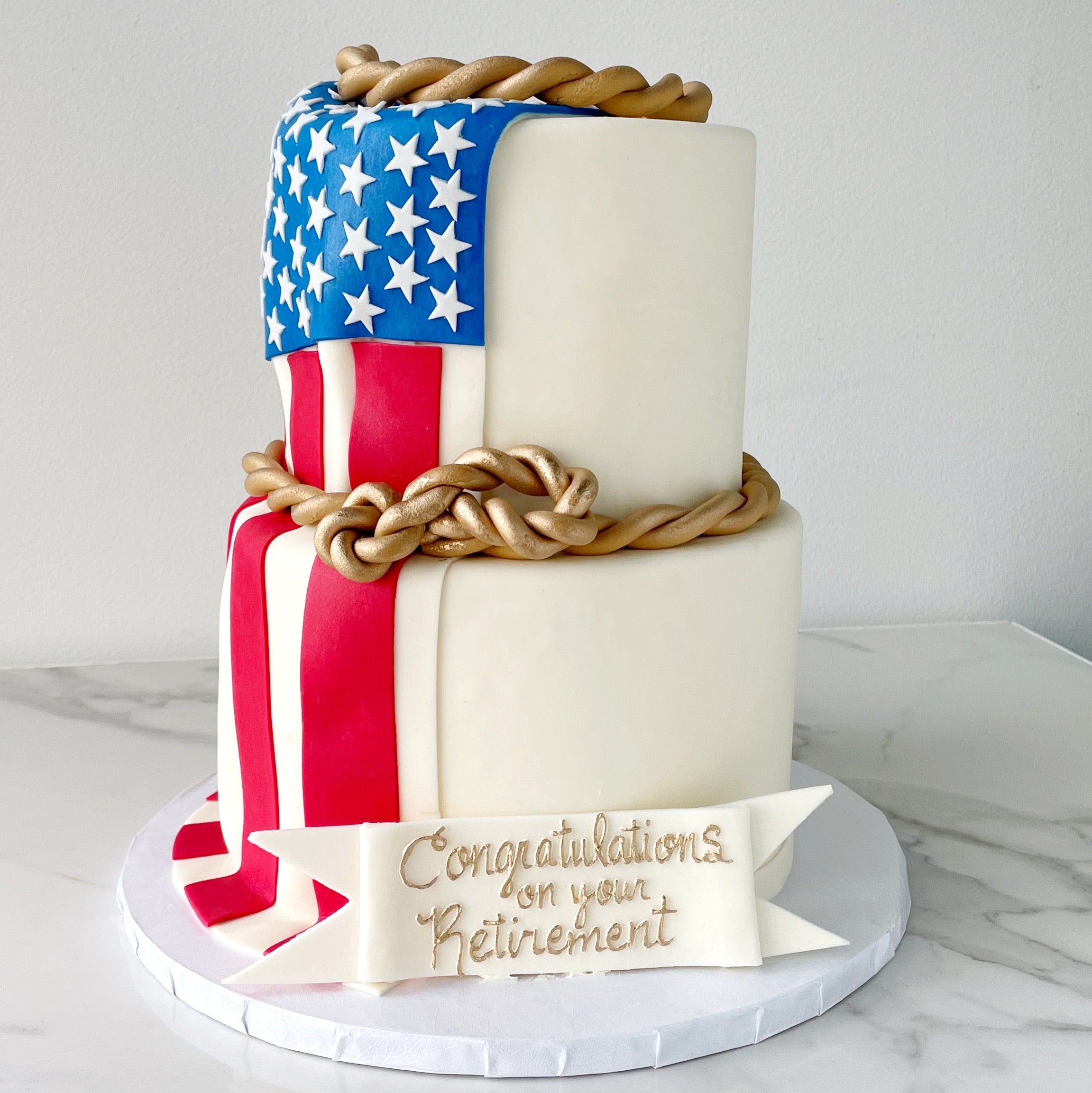 Two-tier cake with American flag design and 'Congratulations on your Retirement' message.