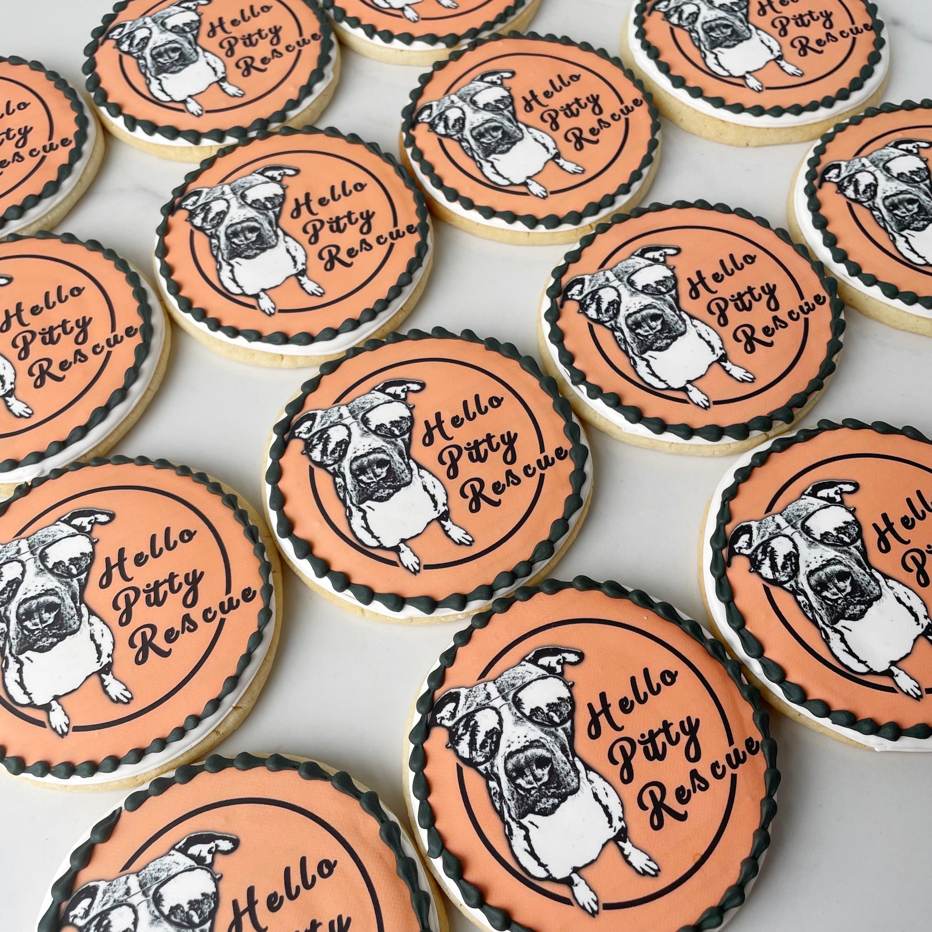Cookies with dog illustrations and 'Hello Pitty Rescue' text on an orange background