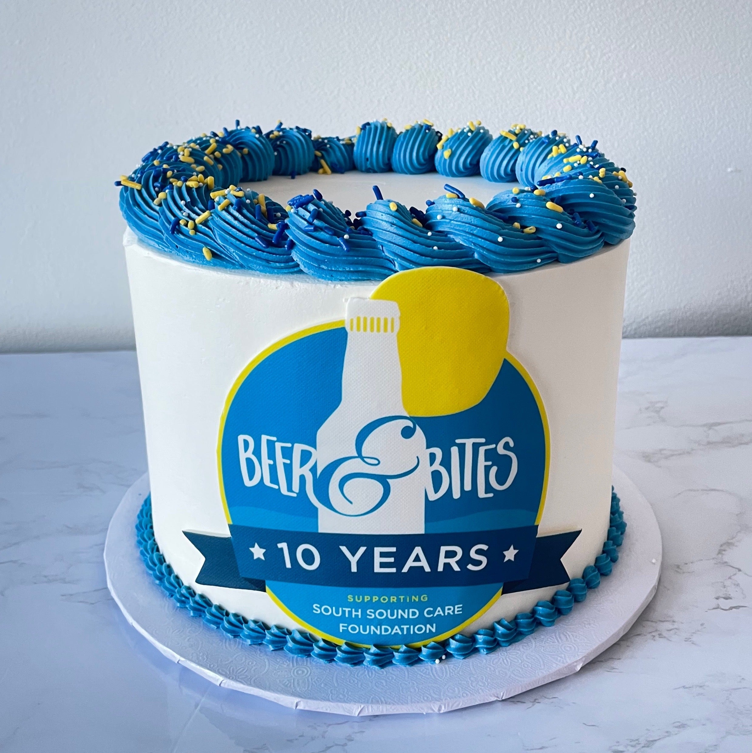 Cake with blue and yellow icing, featuring 'Beer Bites' logo and text on a white background.