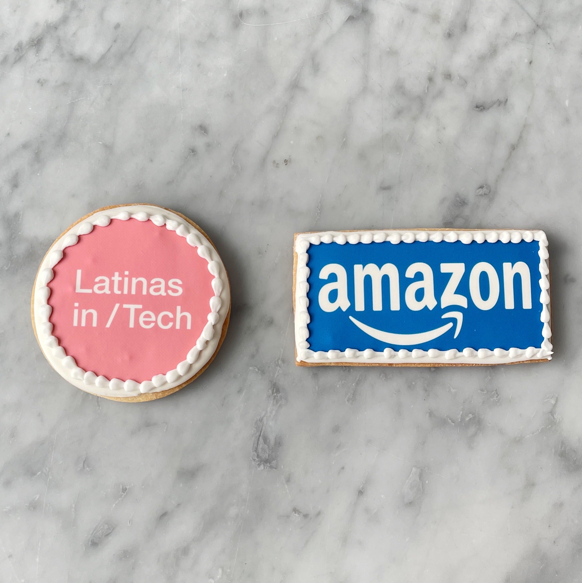 Two cookies on a marble surface, one pink with 'Latinas in Tech' text .
