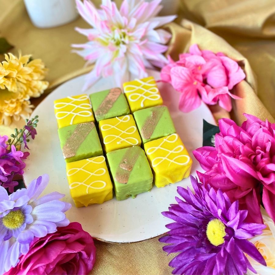 Decorative petit fours on a plate surrounded by colorful flowers