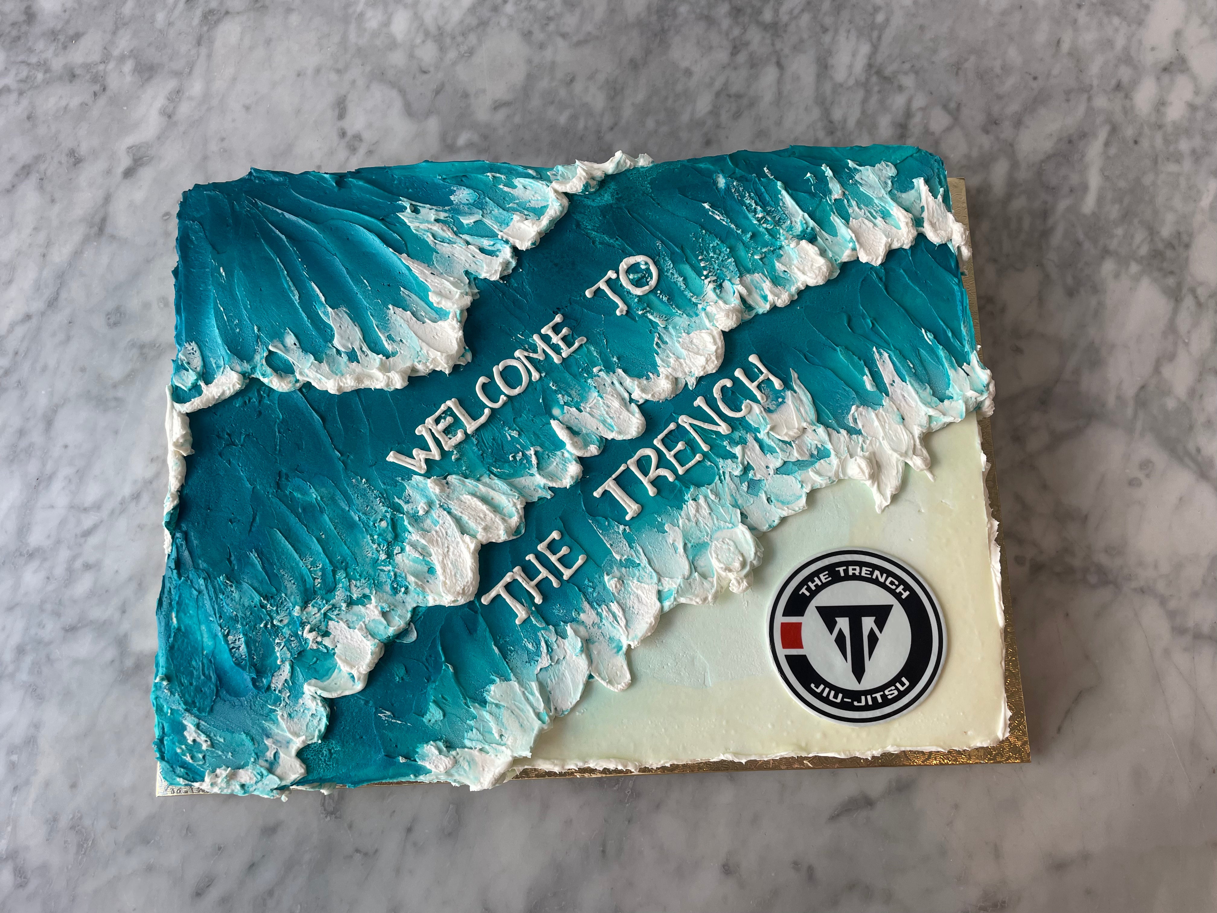 Decorative stone with 'Welcome to The Trench' text and a logo on a cake