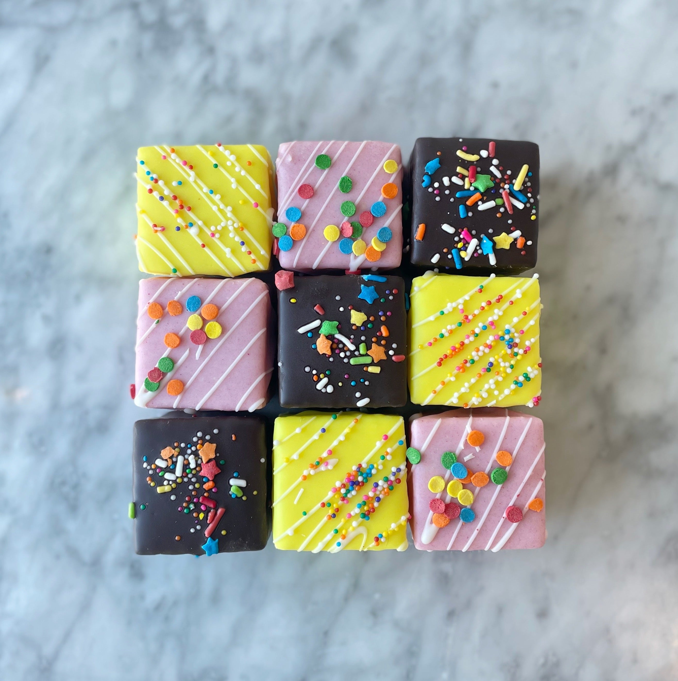 Nine square pieces of petit fours with colorful sprinkles