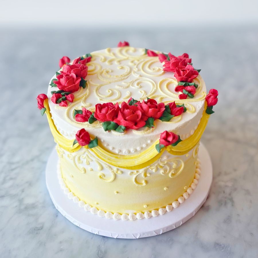 Two-tiered cake with red floral decorations on a marble surface