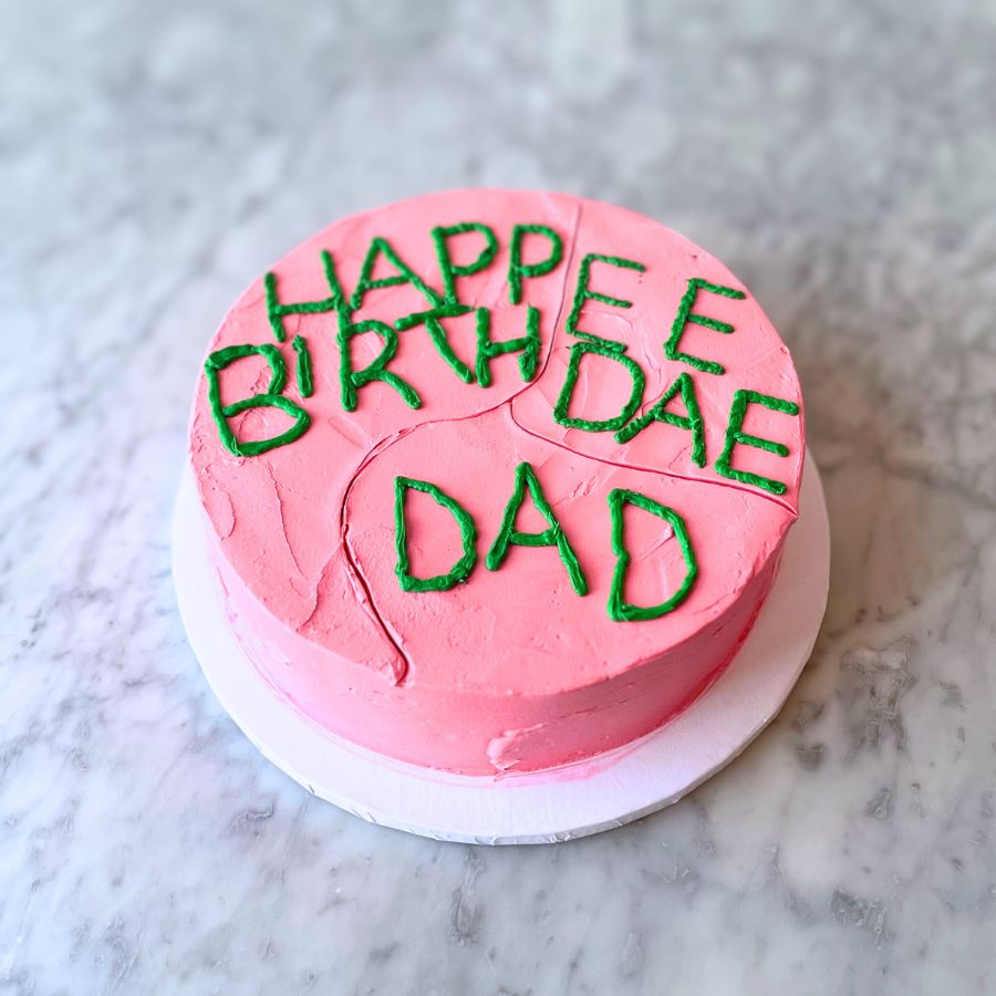 Pink birthday cake inspired from the HP series with green text on a marble surface