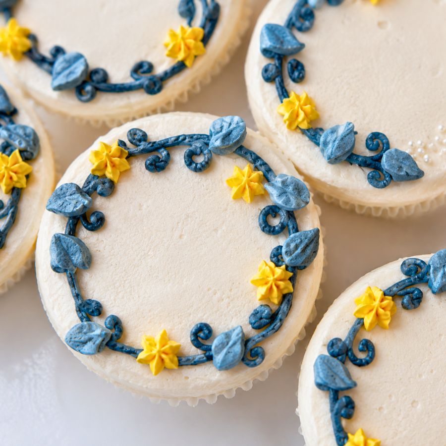 Decorative cupcakes with blue and yellow icing on a white surface