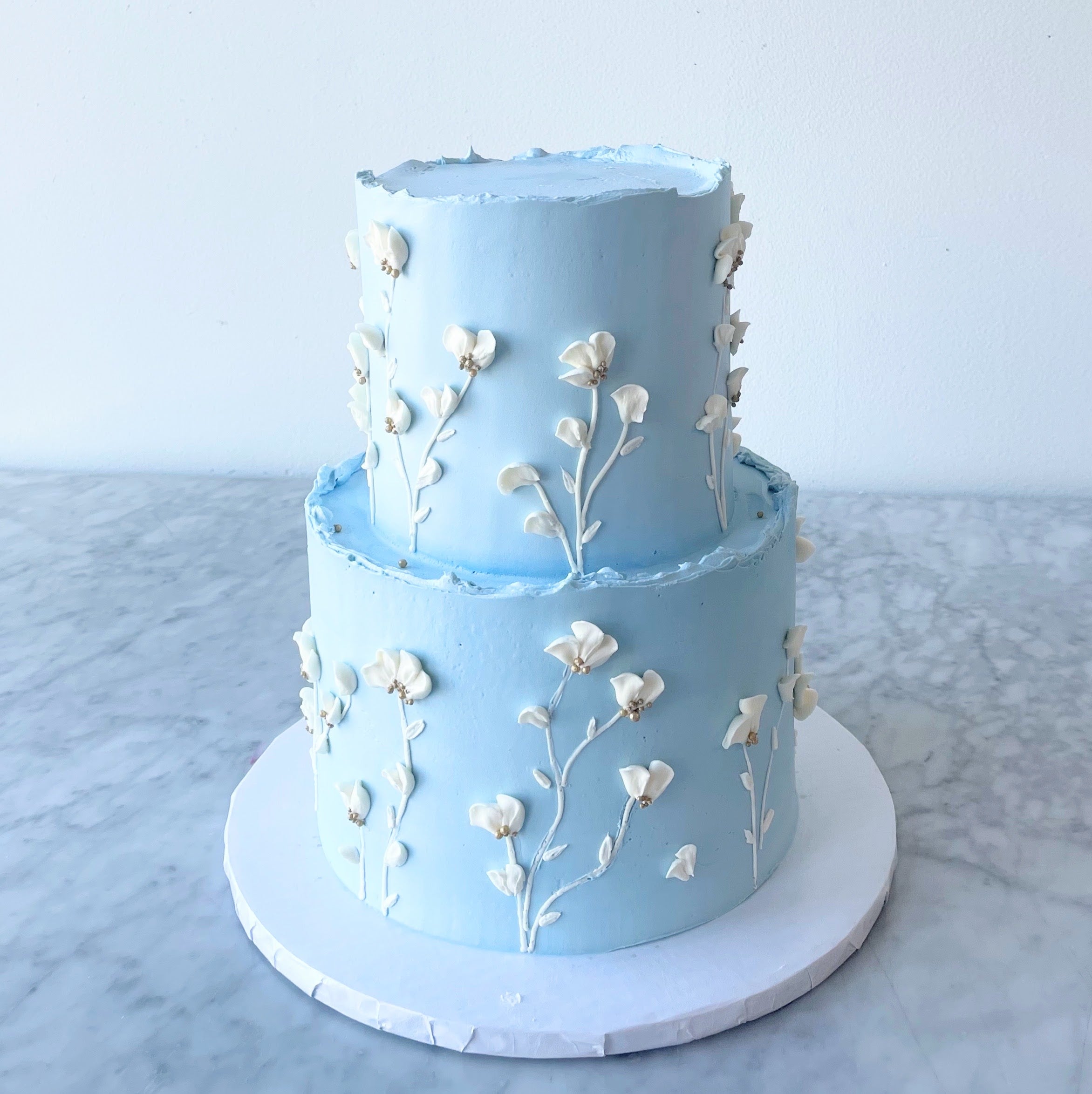 Light blue two-tier cake decorated with white and yellow flowers