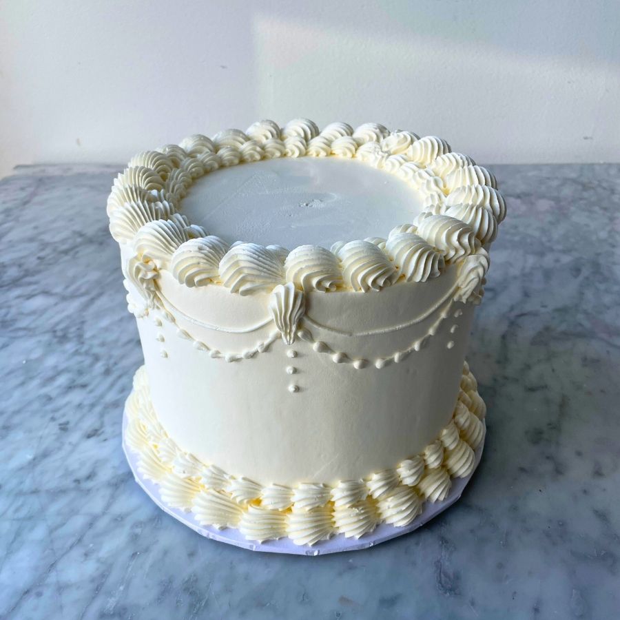 White cake with decorative icing on a marble surface