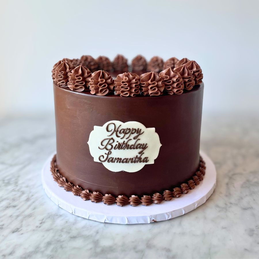 Chocolate birthday cake with 'Happy Birthday Samantha' on a marble surface